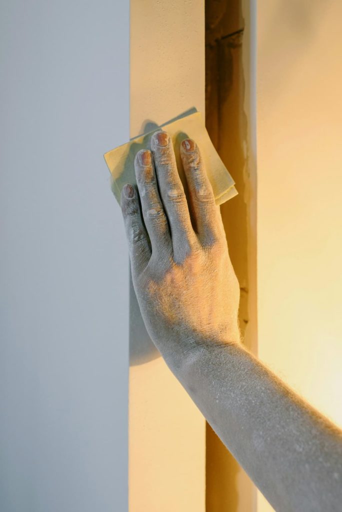 a hand sanding a doorway during redecorating